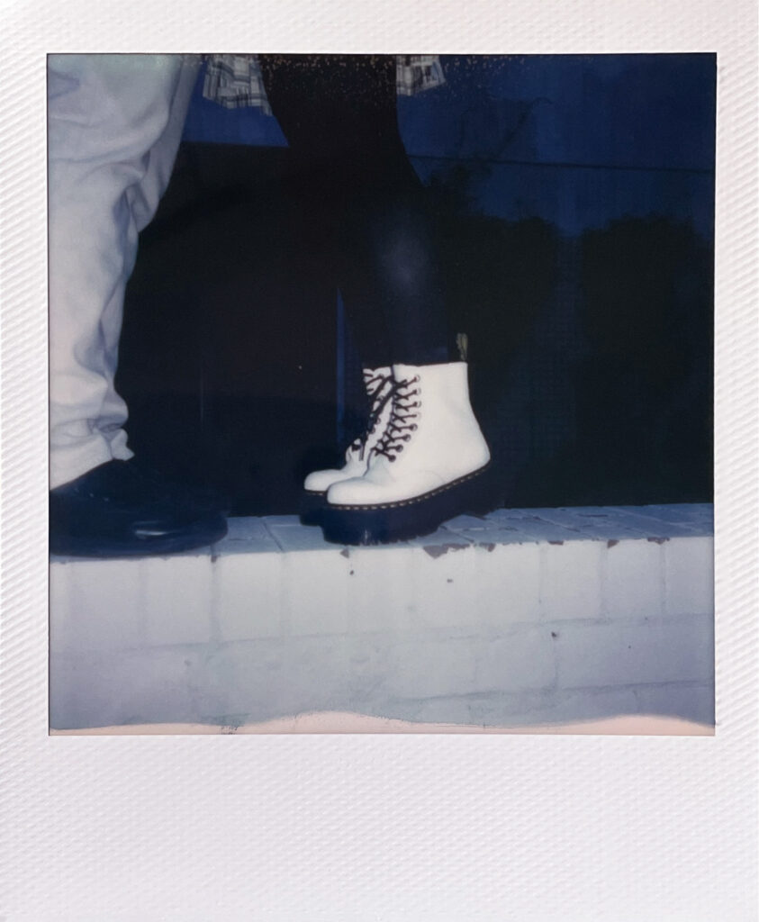 polaroid of the couples shoes, she is tip toeing to kiss him