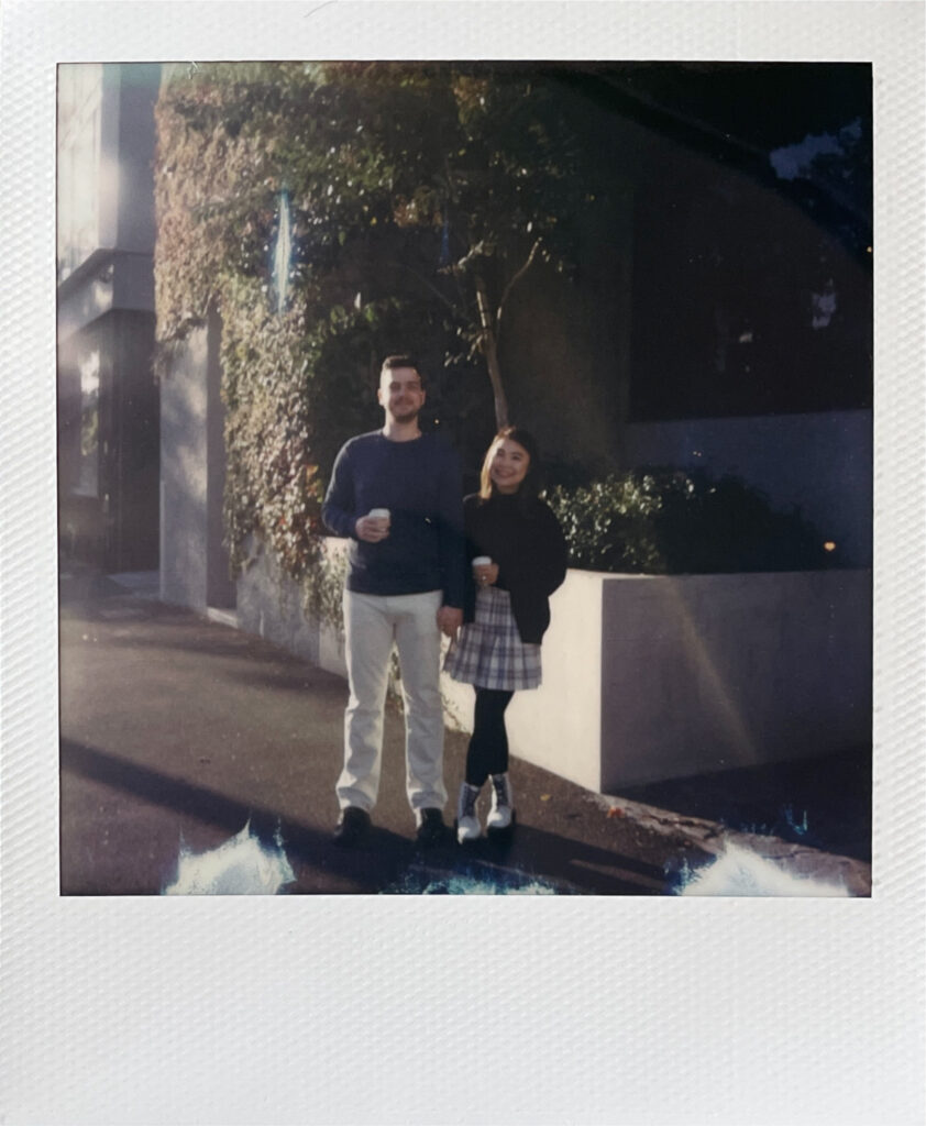 polaroid of couple smiling and holding coffees together