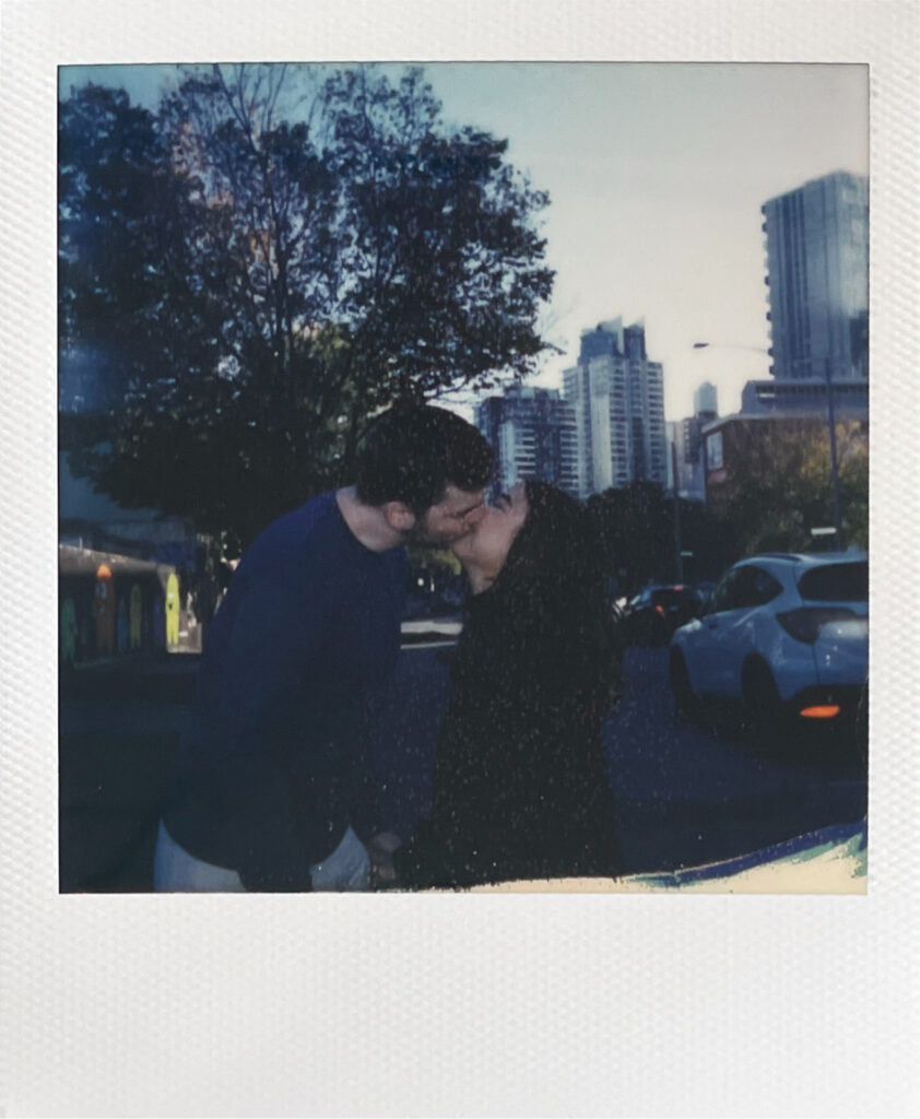 couple kissing on polaroid with the Melbourne city scape behind them