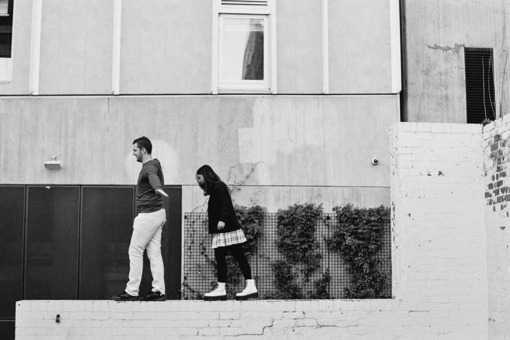 Couple playfully balancing on a wall together