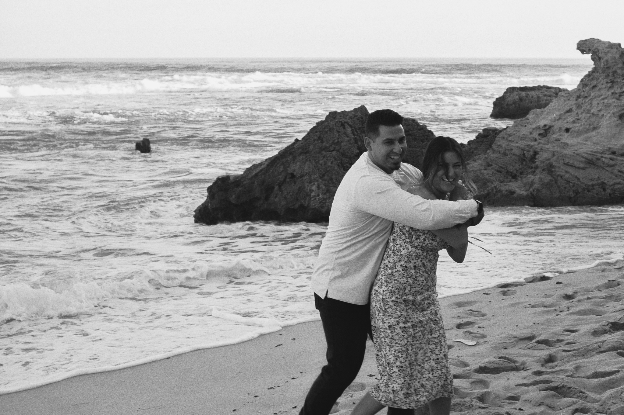 Couple playing around and hugging together on the beach