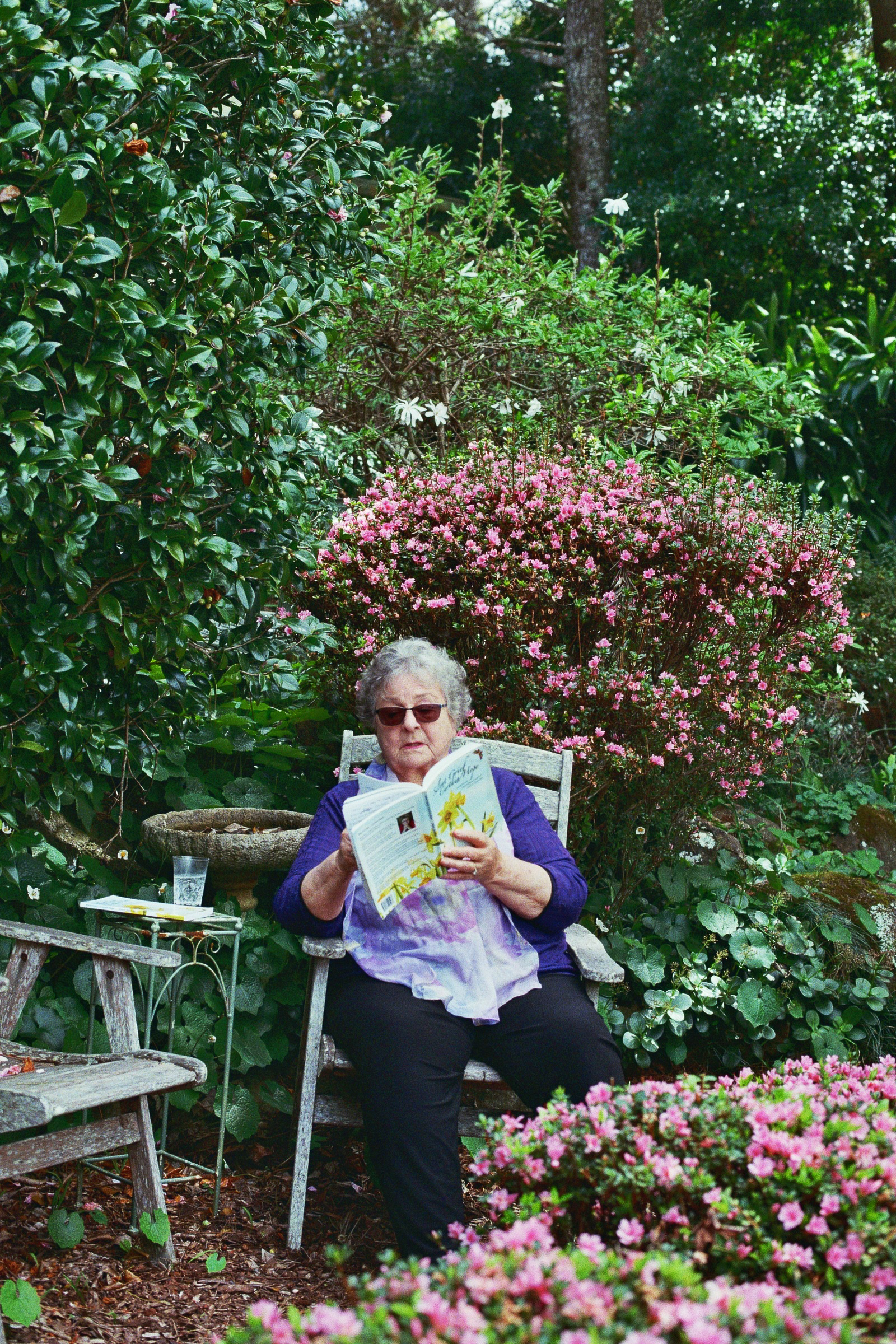 Old lady reading poetry from her book in her garden