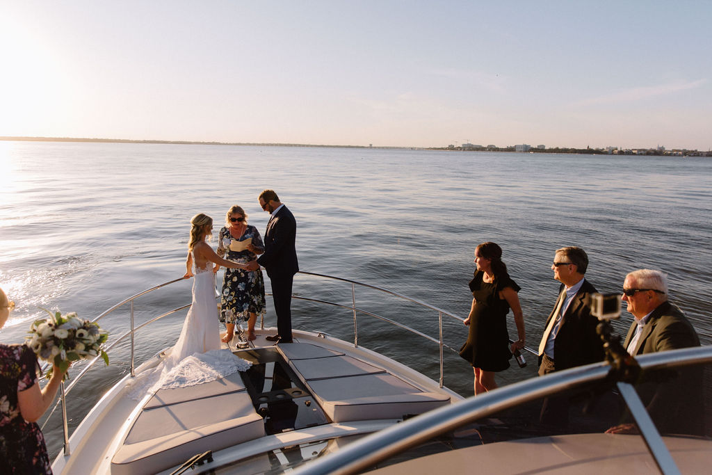 Bride and groom getting married on a sail boat during sunset while their closest friends and family join them