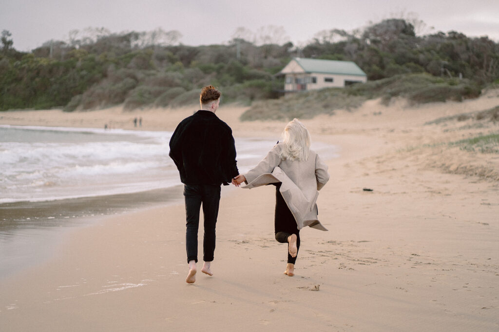 Sunset engagement session on the beach at Cape Paterson, couple running together hand in hand after getting engaged - 2