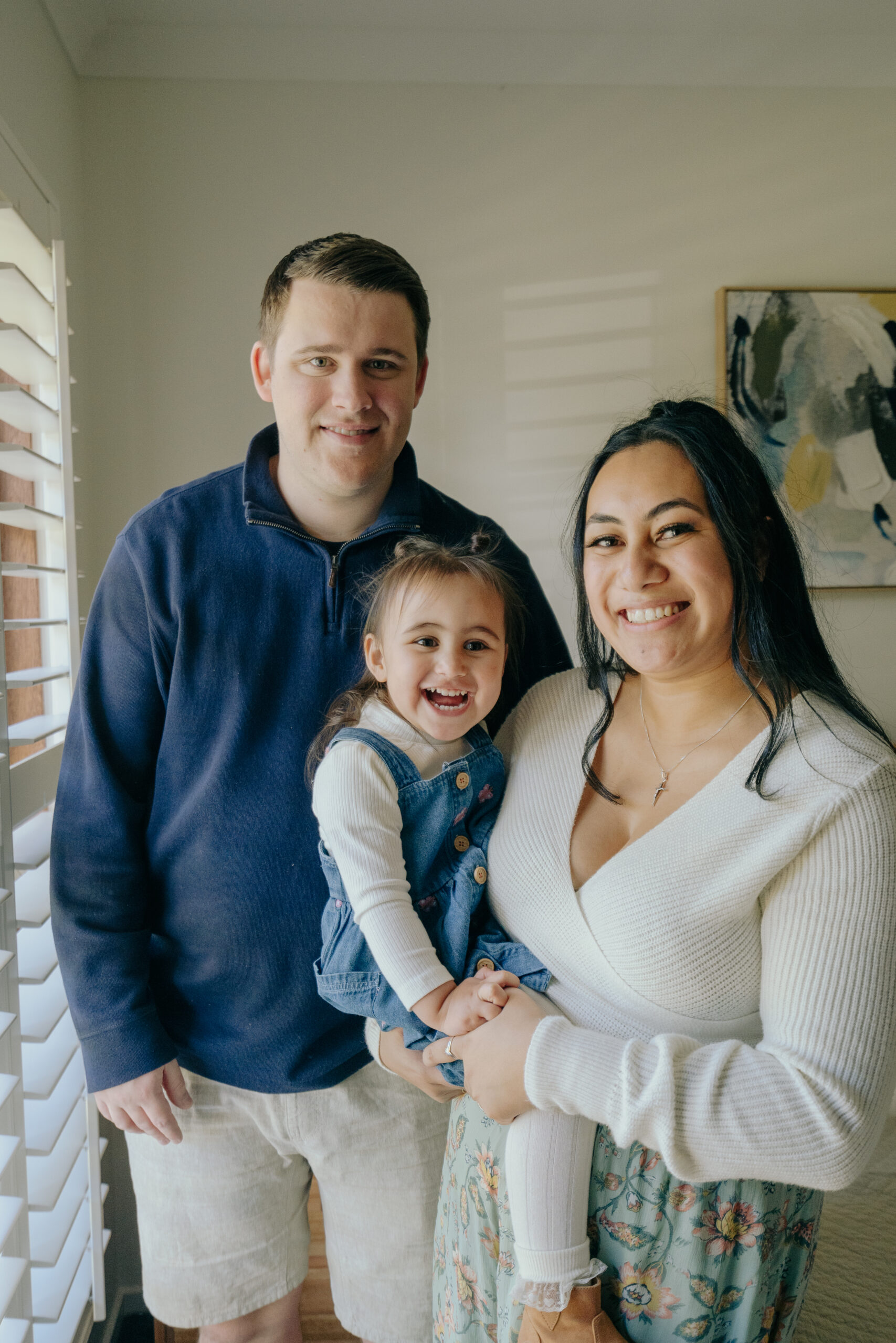 Mum and dad holding 3 year old daughter, wearing matching blue outfits