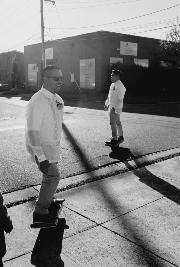 A black and white photo of the groom and his best man riding around on one wheelers before his wedding day