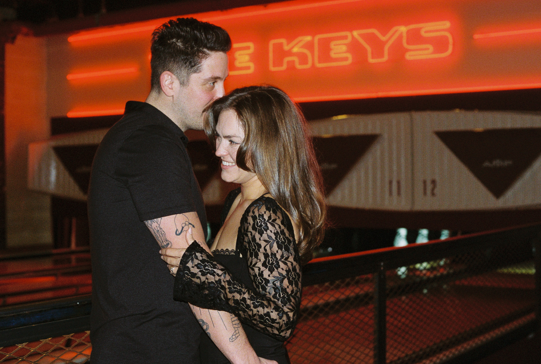 couple hugging in front of a neon sign and bowling lanes