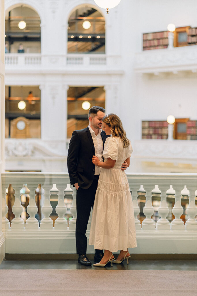 A couple is holding each other with the levels of the melbourne state library showing in the background