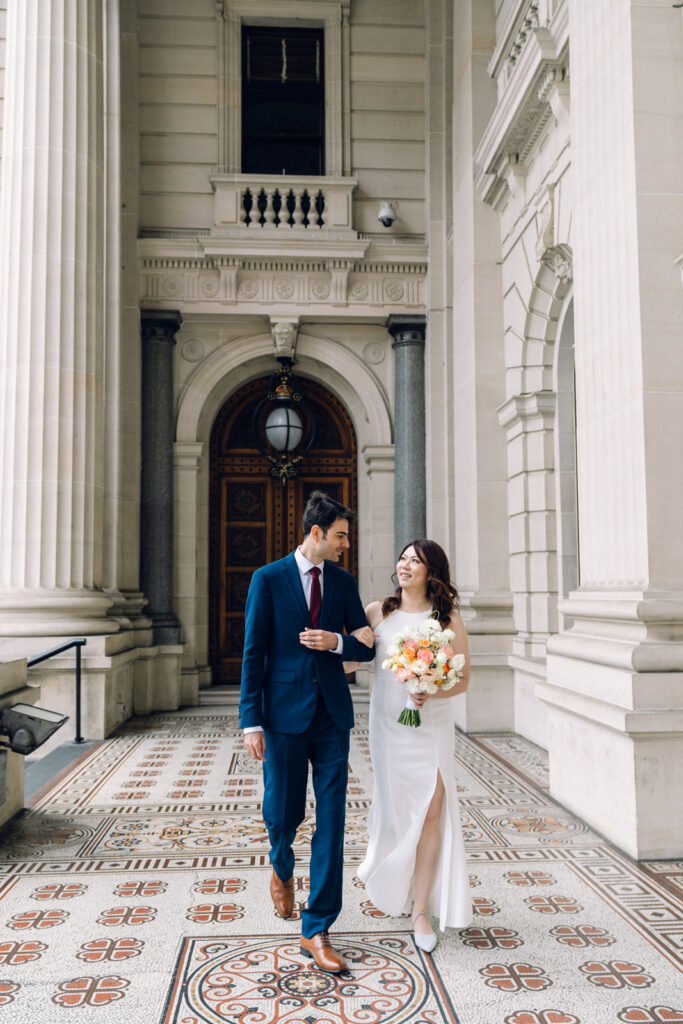 bride and groom walking and laughing together at the parliament house in melbourne