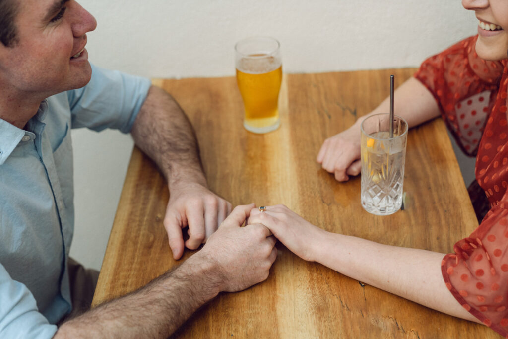 a couple holding hand across a table in a bar while they share a drink together