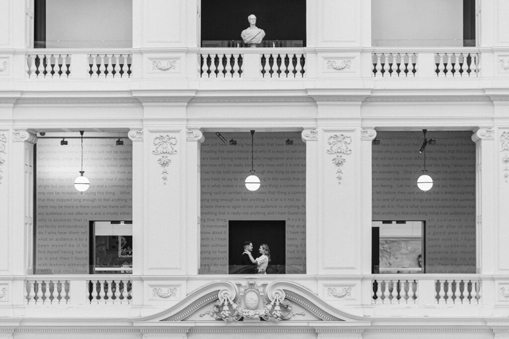 Couple hugging on the balcony in the melbourne state library for their engagement photos