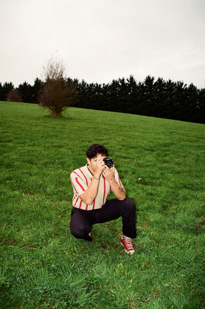 a man taking a photo with an analog film camera in an open field