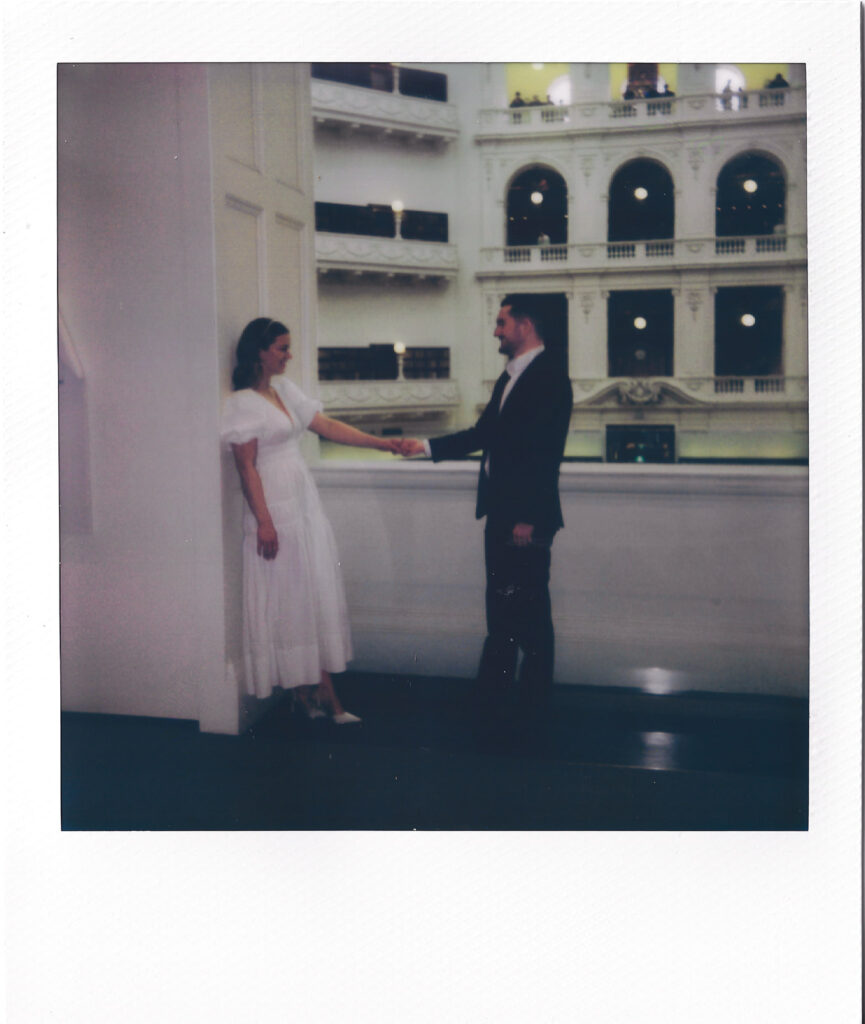 couple holding hands on polaroid, the floors of the state library are visible behind them