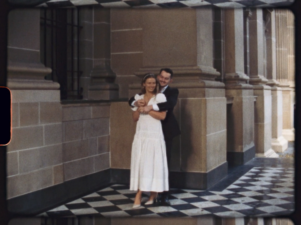 a super 8 snippet of a couple holding each other at the front of the state library of Victoria