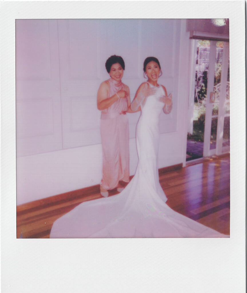 Bride laughing with her mum on polaroid while she's getting ready for her wedding 