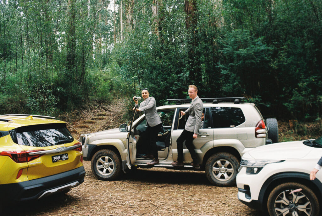 a film photo of groomsman hanging out of a four wheel drive and filming on a camcorder on zoe and calebs wedding day