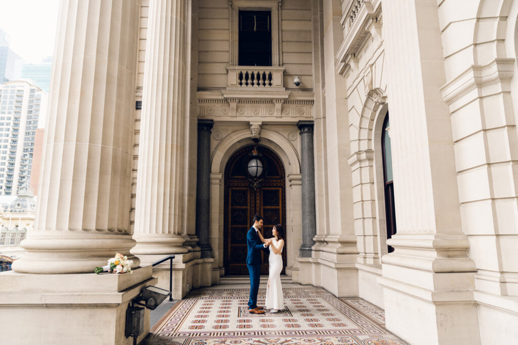 couple waltzing together at the parliament house on their wedding day, he is in a blue suit