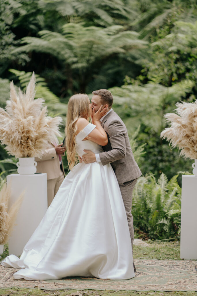 couple sharing their first kiss as husband and wife in the middle of the forest at Toolangi heights, they are standing on a Persian rug and surrounded by dried florals