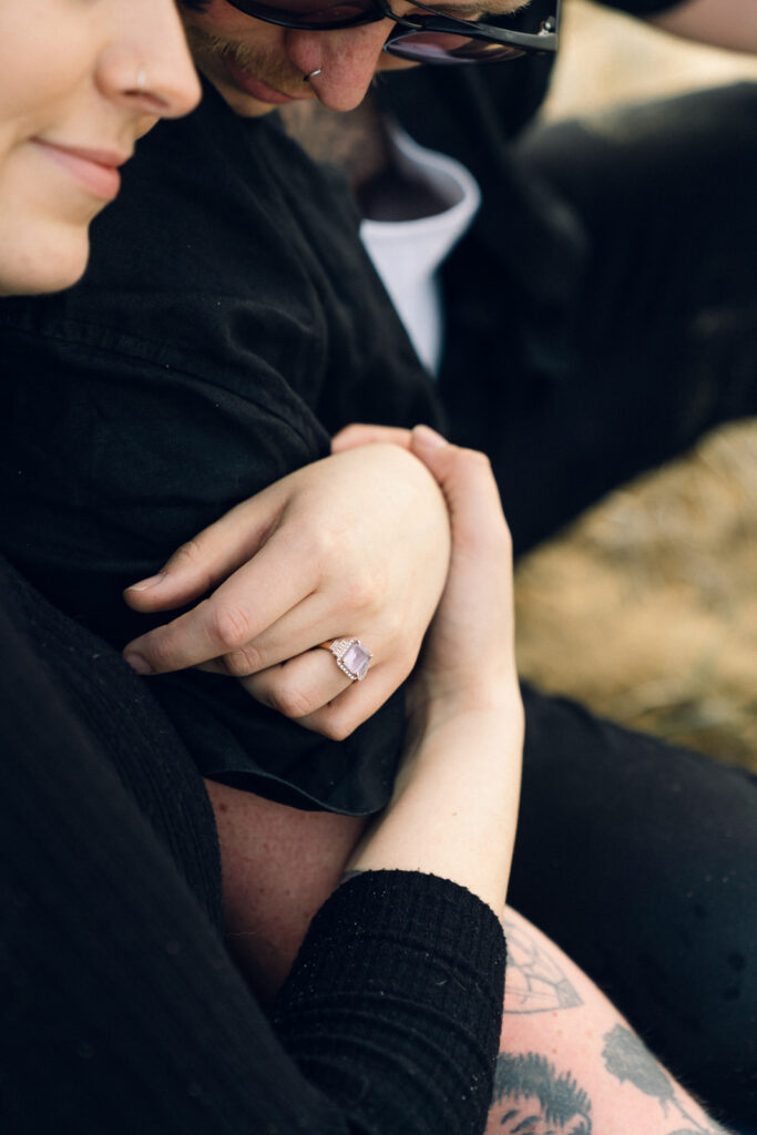 a couple hugging, an amethyst engagement ring is visible