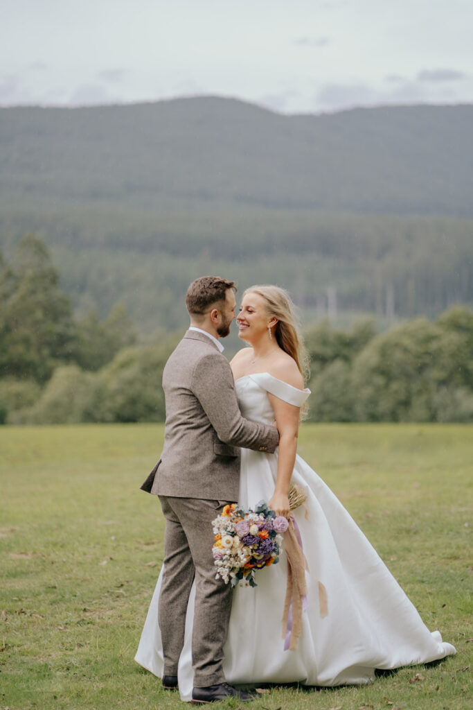 couple hugging on their wedding day, just married with the mountains of Toolangi Heights behind them