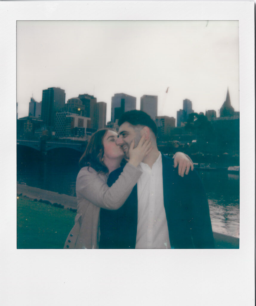 A polaroid of a couple kissing during their pre-wedding photography, southbank melbourne cityline is visible in the background