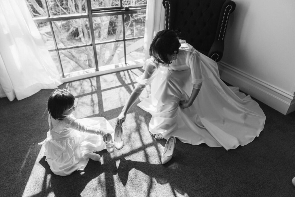 a bride showing her shoes to the flower girl