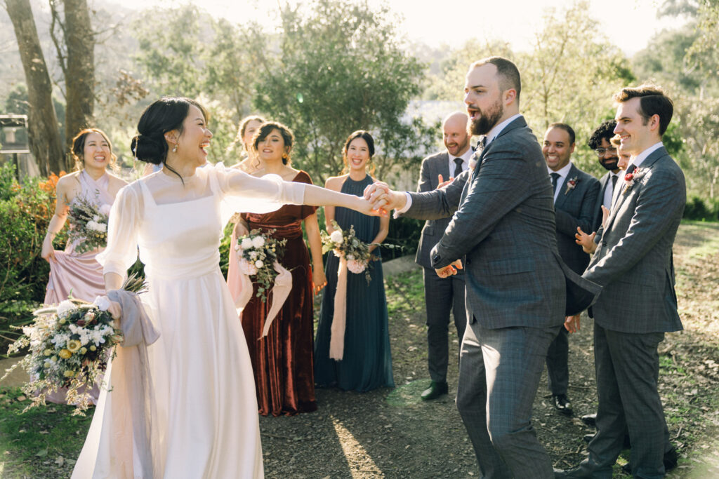 bride and groom dancing together while their bridal party cheers behind them