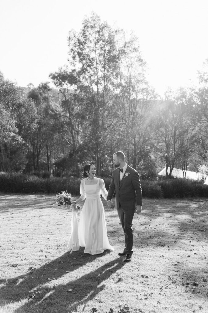 bride and groom walking hand in hand in the paddocks of potters receptions