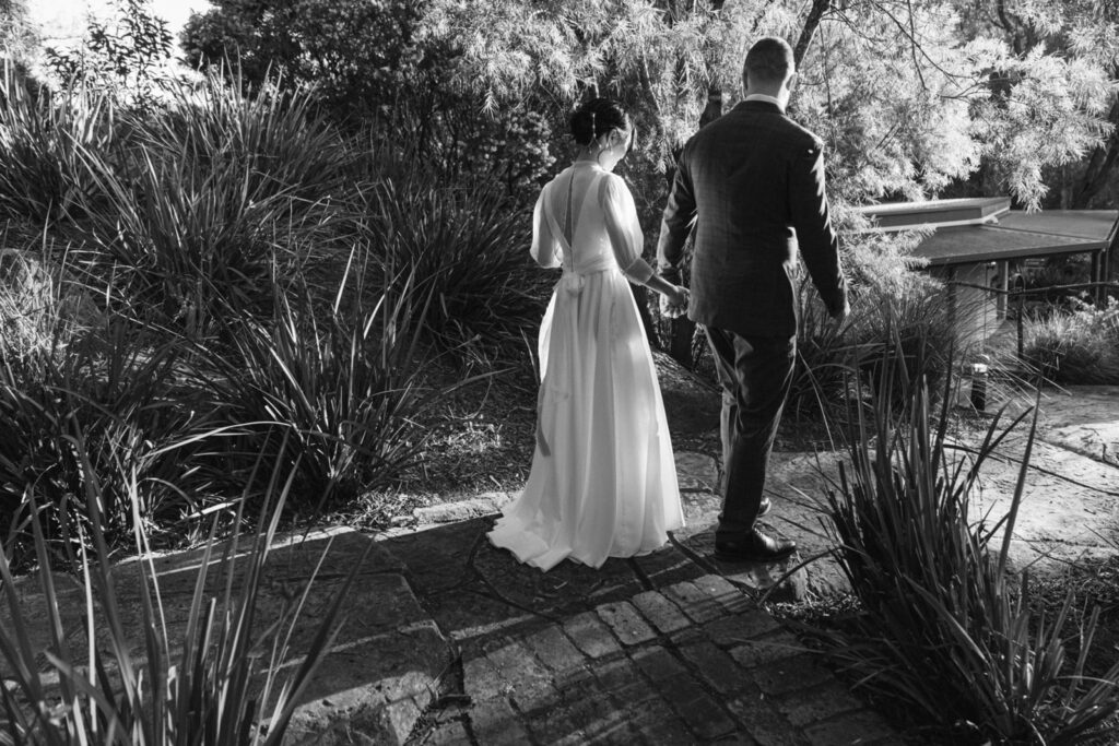 bride and groom walking hand in hand through the pathways of potters receptions