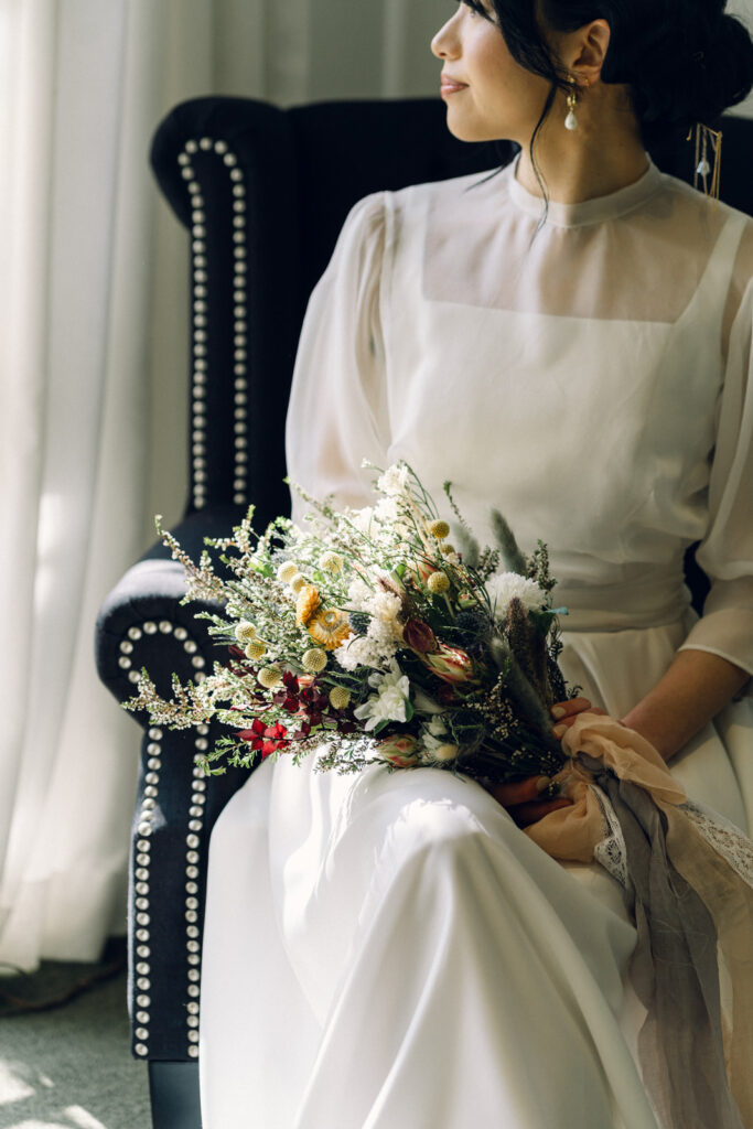 bride sitting in the bridal suite at potters receptions on a velvet black chair 