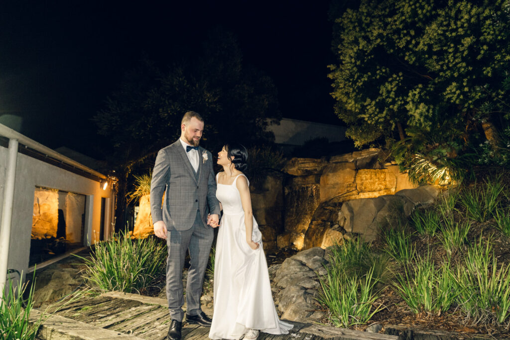 bride and groom holding hands in front of the water feature at potters receptions