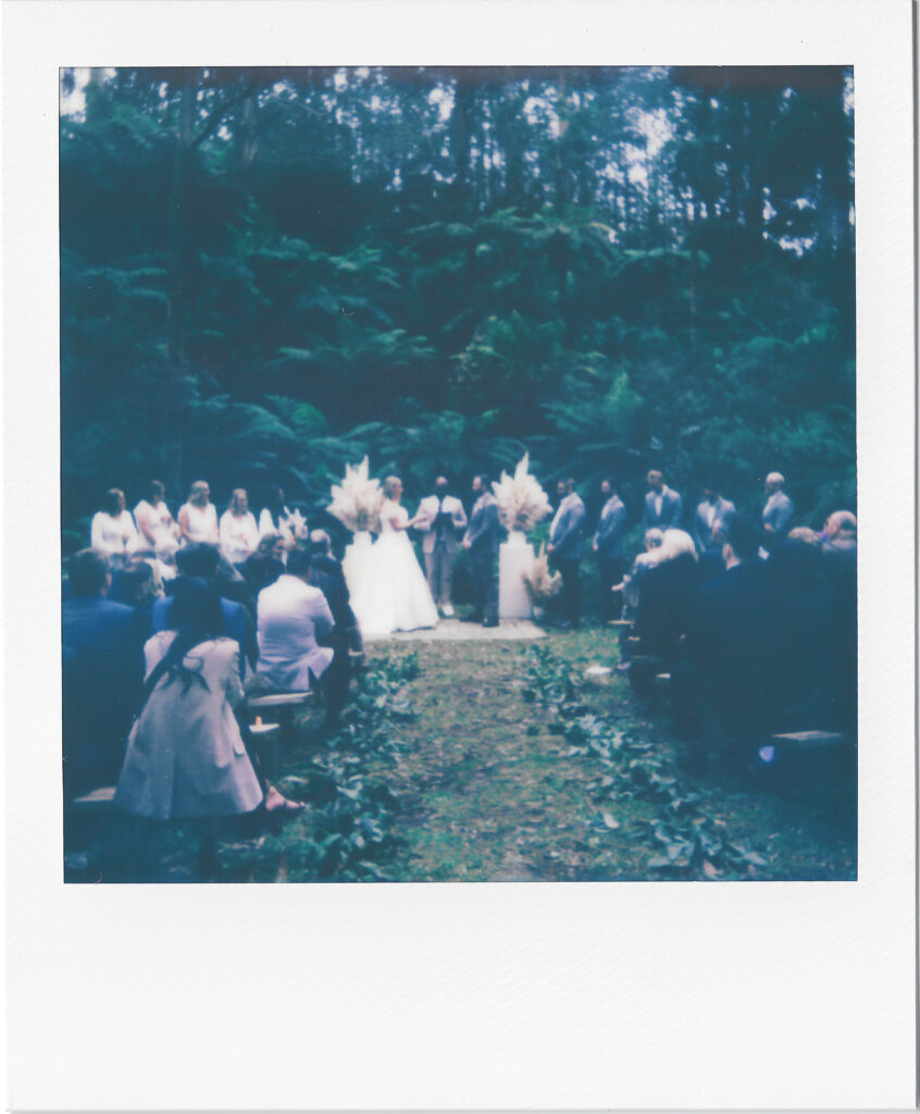 a polaroid photo of a couple during their wedding ceremony in the middle of a forest