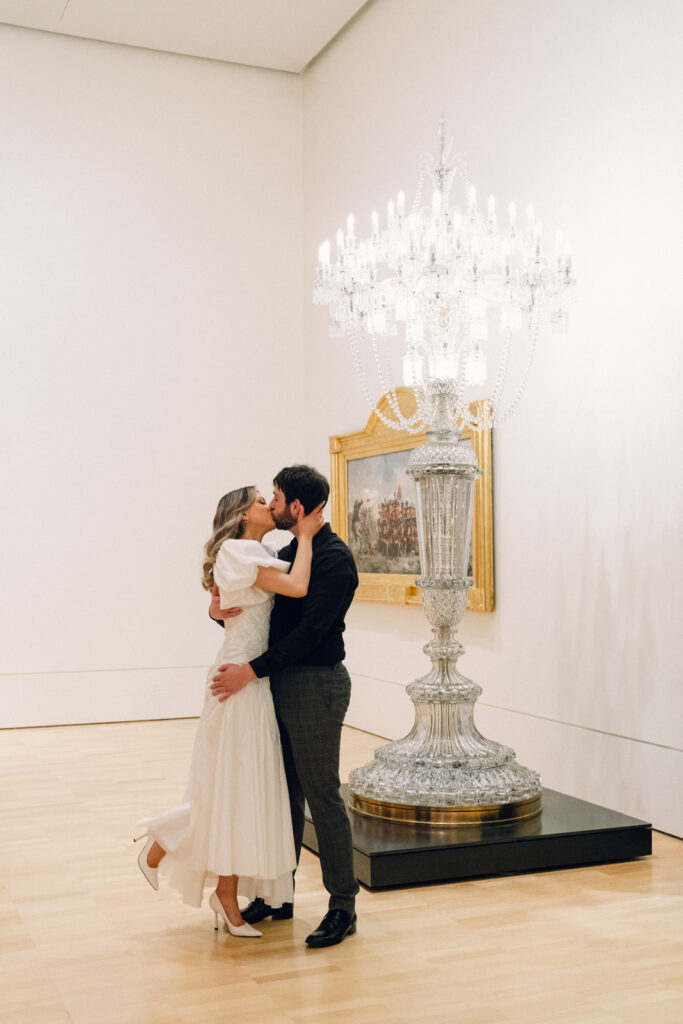 couple kissing during their engagement photos in front of a tower of chandeliers at the national gallery of victoria