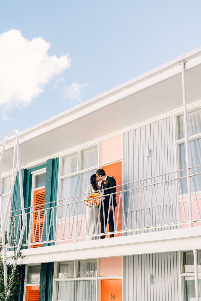 bride and groom kissing on the top floor of the colourful astor motel