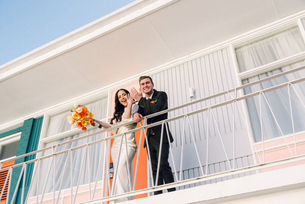 bride and groom showing off their wedding rings from the balcony of the colourful astor motel