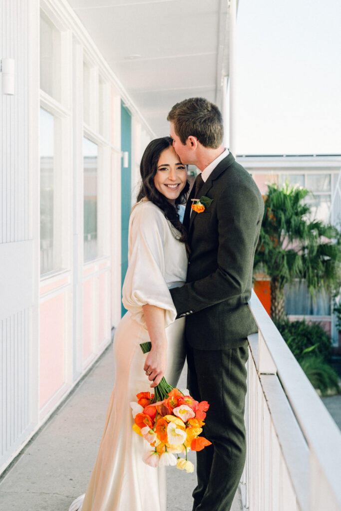 groom kissing bride on the forehead on the balcony of astor motel