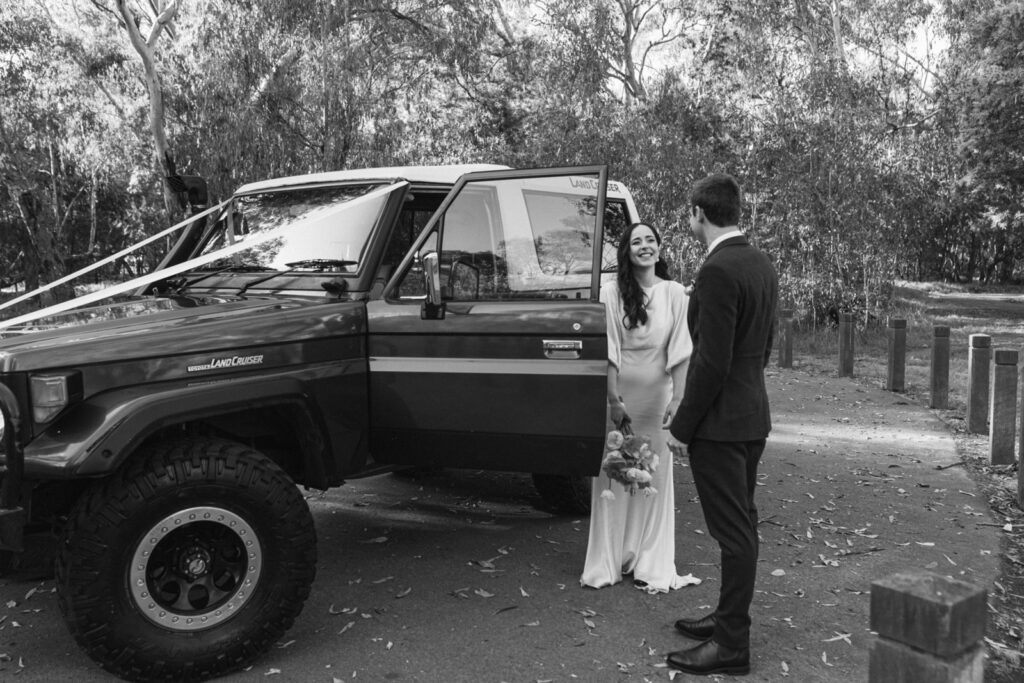 a bride and groom standing in front of their bridal car, a land cruiser