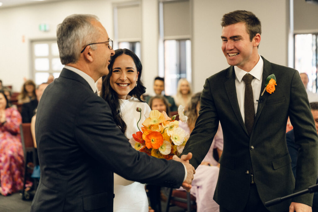 groom shaking brides hand when she arrives at the altar