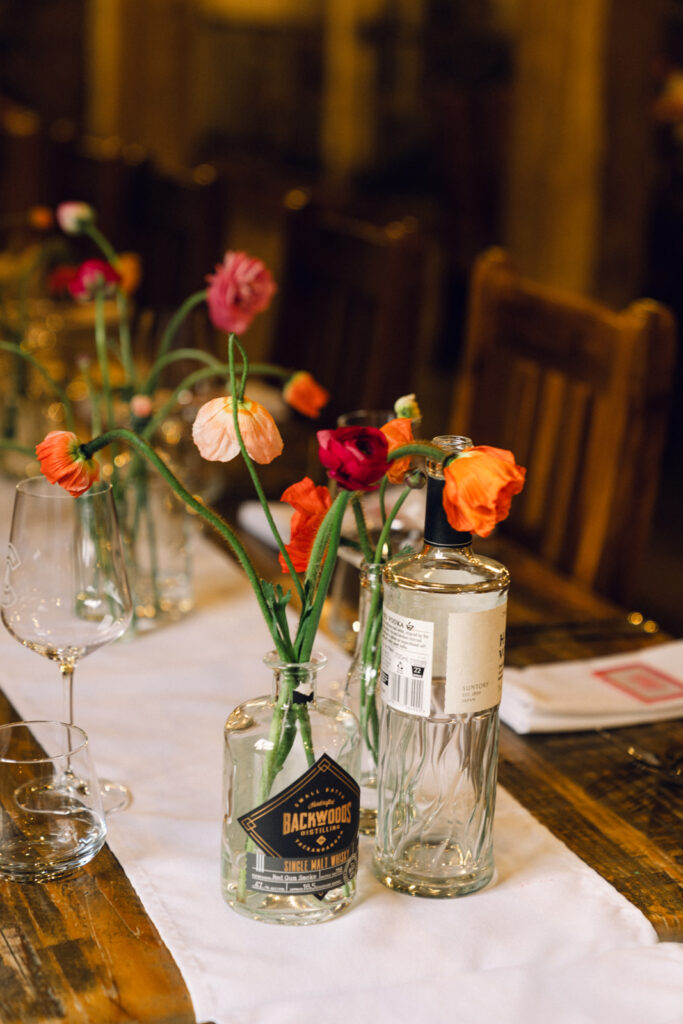 colourful bud vases in whisky bottles