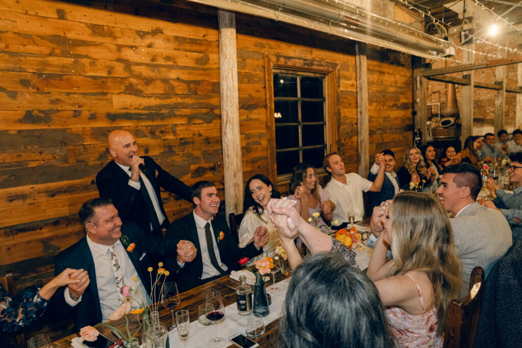 couple and their guest holding hands seated at the table together at corowa distillery