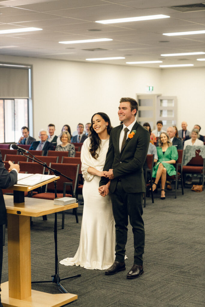 bride and groom smiling at the front of the church during their wedding ceremony