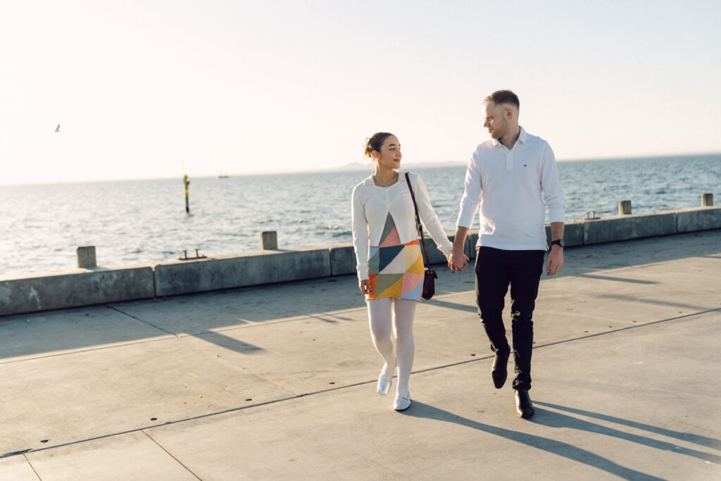 couple holding hands on the portarlington pier during their engagement session at the beach