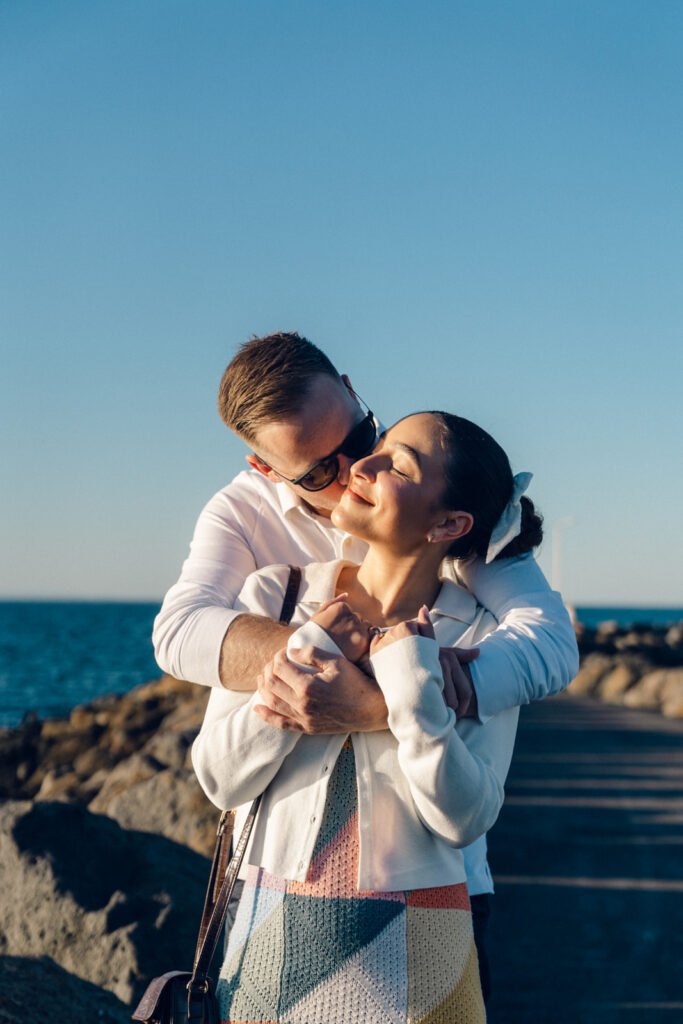 couple hugging in during a beach engagement session sunset at portarlington pier