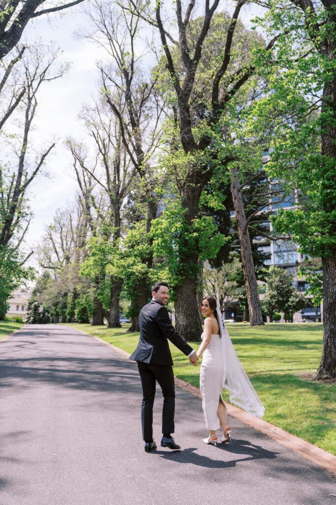 Bride and groom walking through Fitzroy Gardens together