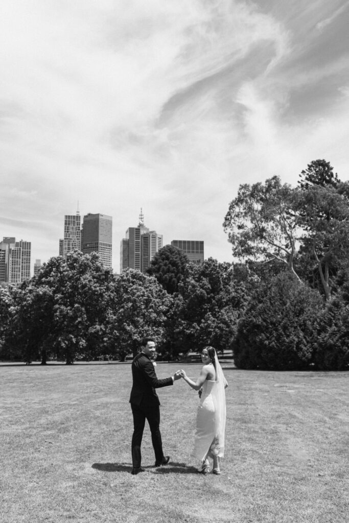 black and white photo of bride and groom with the melbourne city skyline in the background