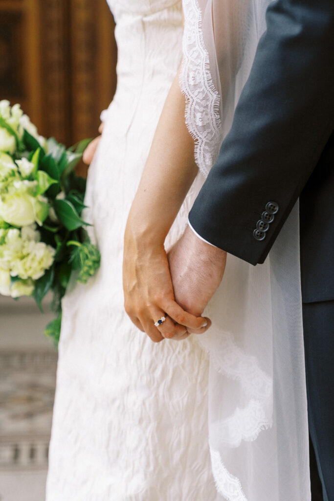 a closeup of bride and groom holding hands in parliament house