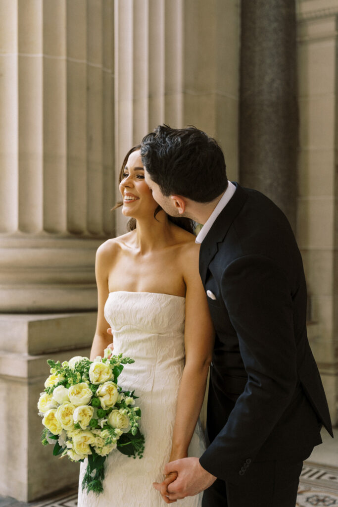 groom kissing bride on the cheek at parliament house