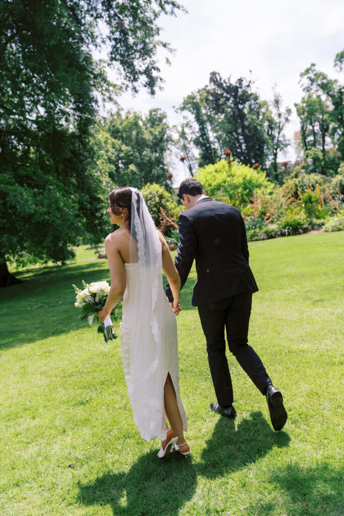 Bride and groom walking through Fitzroy Gardens together during their elopement