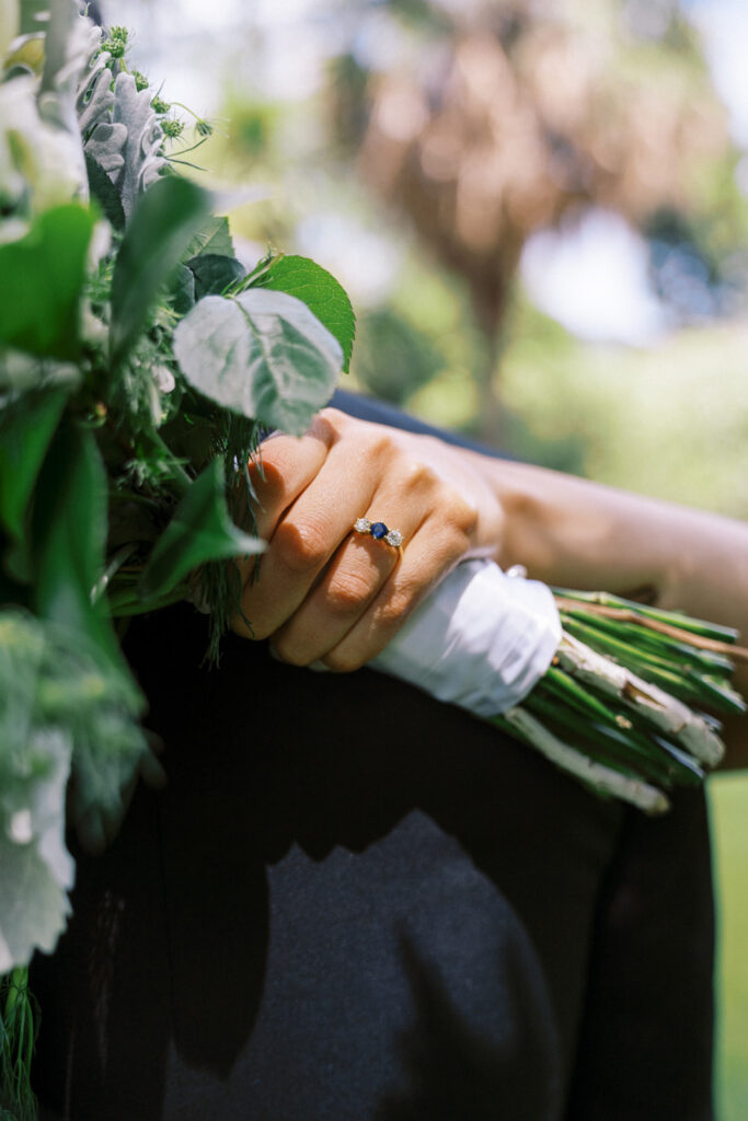 a closeup of the blue engagement ring with the wedding bouquet