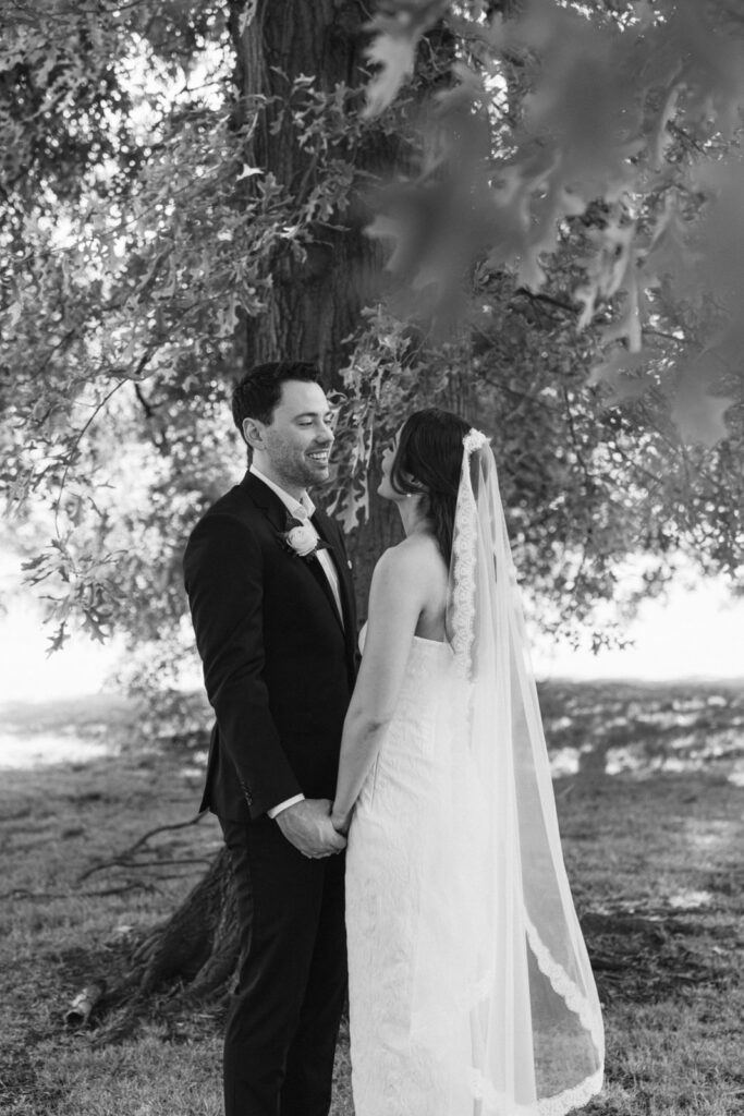 a bride and groom under a tree in fitzroy gardens